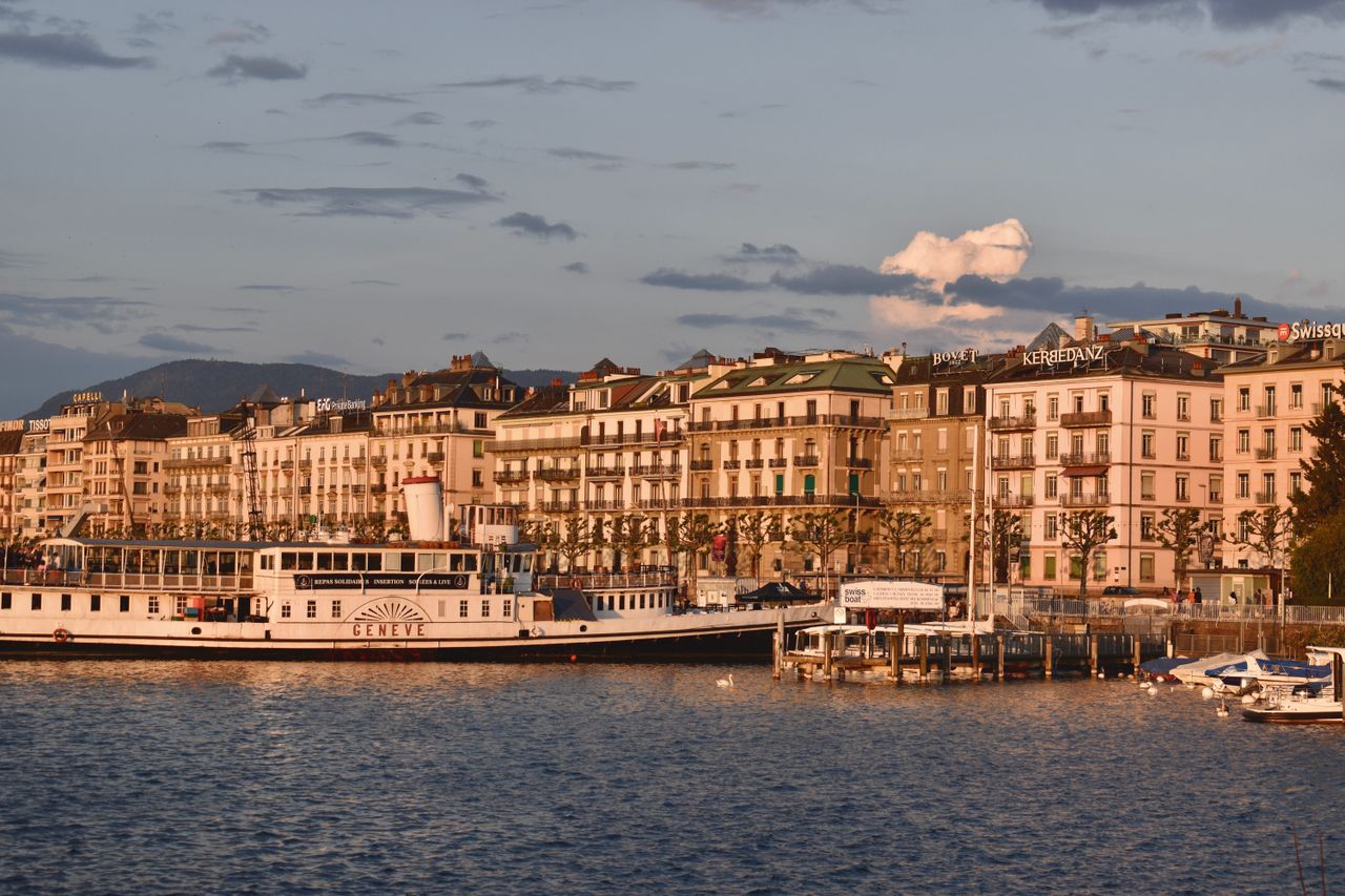 Elegant view of Genevas waterfront with historic architecture at sunset.